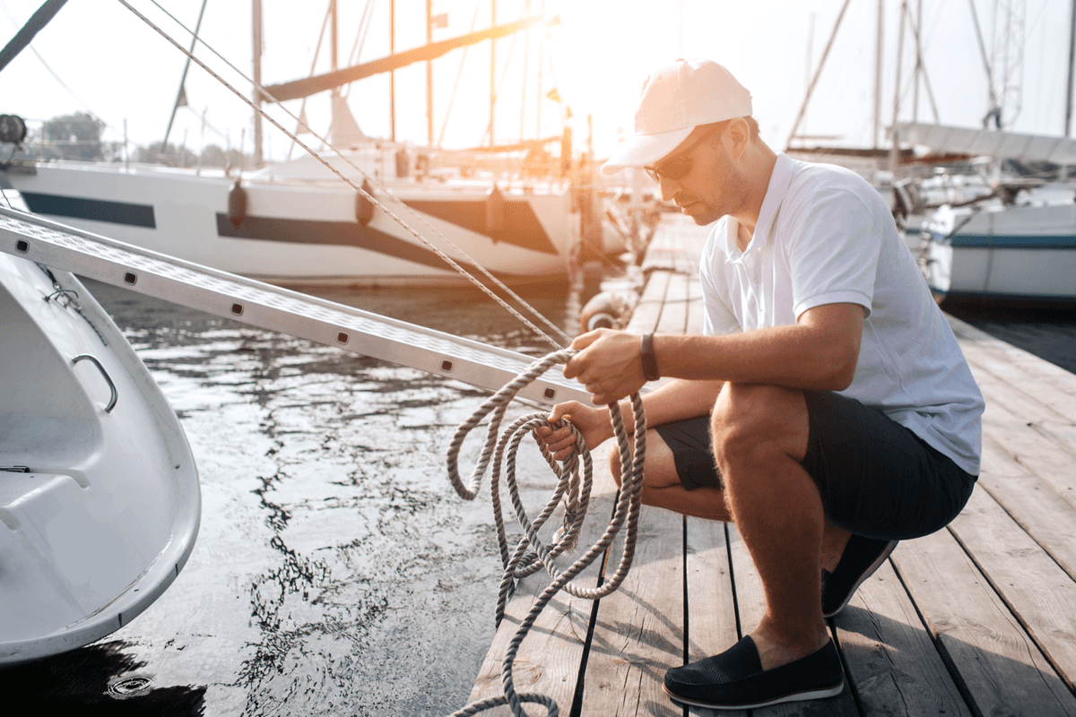 A marine pro handling dock lines beside sailboats