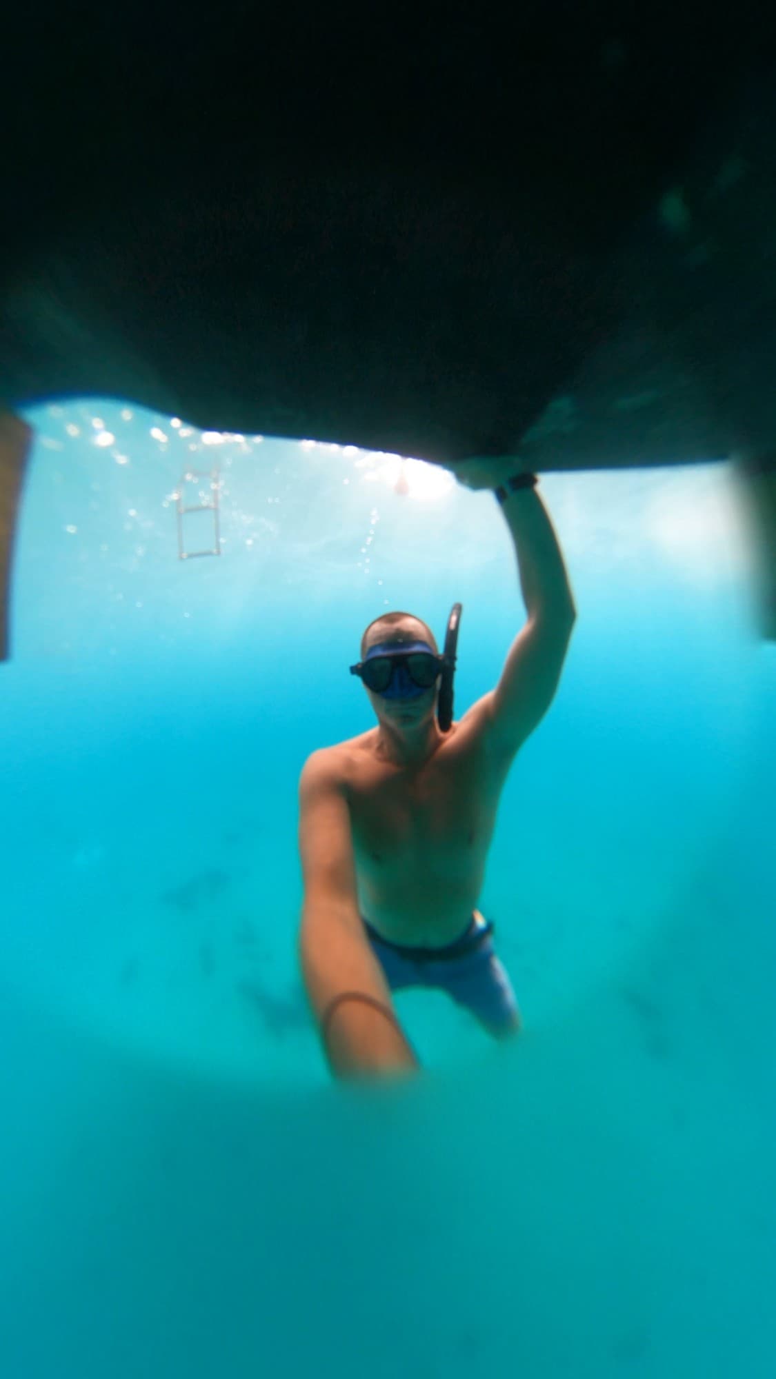 Jacob freediving beneath a hull in clear blue water
